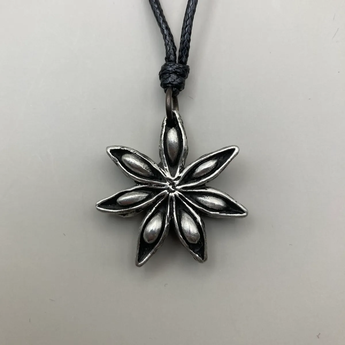 Hänge i tenn i form av stjärnanis med band i läder framsida
